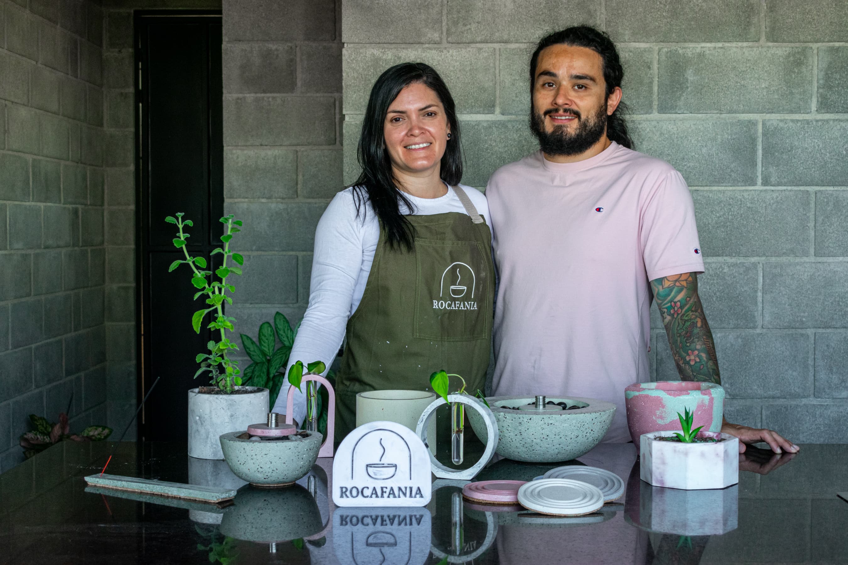 El equipo de ROCAFANIA junto a una mesa con macetas, kits de propagación, un fogonero y portavasos de concreto